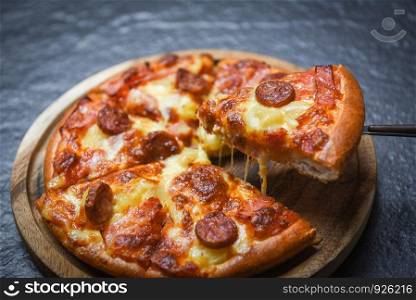 Pizza slice on wooden tray / delicious tasty fast food italian traditional pizza cheese with Mozzarella , Smoked pork sausage , Pineapple ham on topping sauce