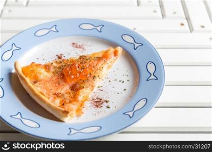 Pizza sliced with smoked salmon and egg on white wooden table