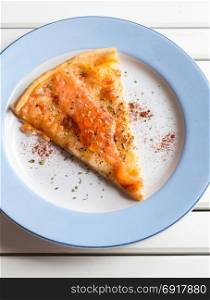 Pizza sliced with smoked salmon and egg on white wooden table
