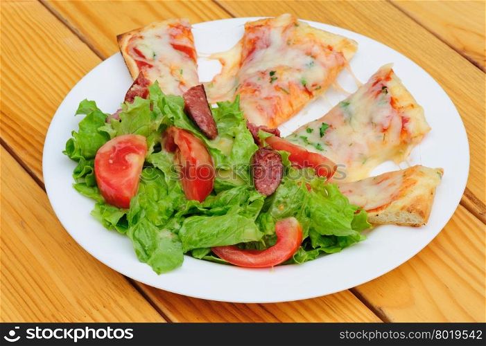 Pizza slices with melted cheese and fresh vegetables salad. Pizza slices and salad