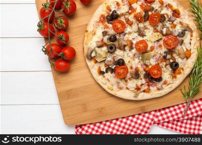 Pizza with bacon, olives and tomato on wooden table