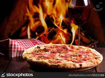 pizza with bacon, salami and glass of wine