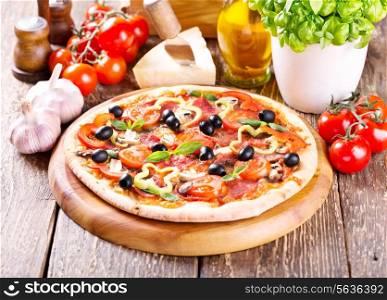 pizza with bacon, vegetables and olives on wooden table