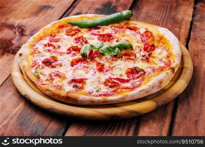 Pizza with basil, red onion and sausage on a wooden board