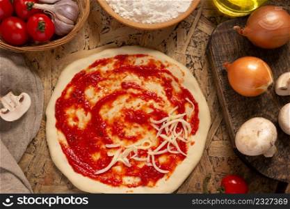 Pizza with cheese and sauce homemade on table. Cooking pizza at wooden tabletop background. Recipe concept in kitchen