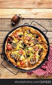 pizza with cheese, tomatoes, mushrooms, ham, sausage and olives on a wooden table, top view