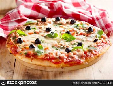 pizza with ham and olives on wooden background