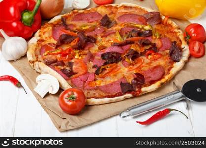 Pizza with ham, salami and chili pepper, on wooden table