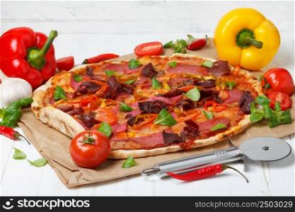 Pizza with ham, salami, pepper and tomato, on wooden table still life