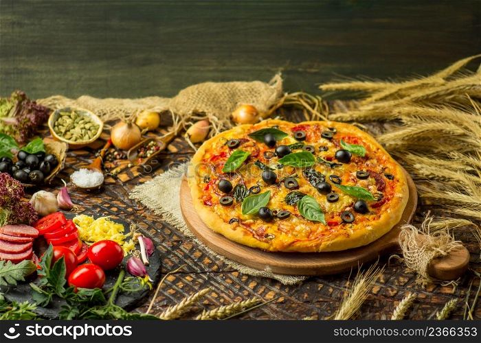 Pizza with ingredients and spices. Pizza on wooden board and various cook ingredients. Green basil and ingredients for pizza. Food ready for cooking. View with copy space. Pizza ingredients on table. Ingredients with pizza dough
