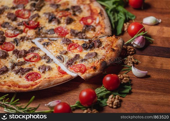 pizza with meat mushrooms and tomato on wooden table background top view