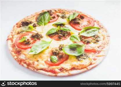 pizza with mozzarella, tomatos and green basil pesto isolated on white