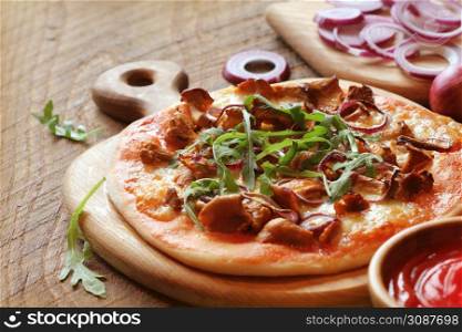 Pizza with mushrooms chanterelle, rucola on wooden table.. Pizza with mushrooms chanterelle, rucola on wooden table