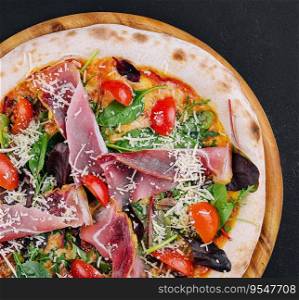 Pizza with prosciutto meat on wooden board