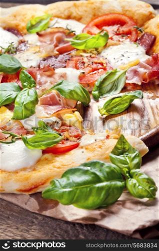 Pizza with prosciutto, mozzarella, tomatoes and basil, selective focus