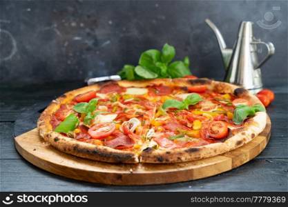 Pizza with salami and tomatoes on blak wooden table. Pizza with salami and tomatoes