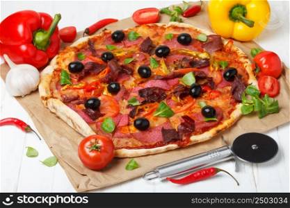 Pizza with salami, ham and black olives on wooden table
