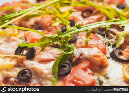 Pizza with salmon, tomatoes and olives. Close up view