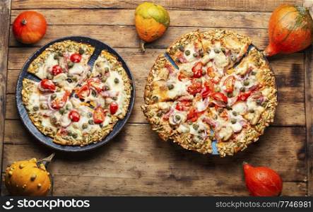 Pizza with sausage, tomato and capers on a pumpkin tortilla. Autumn pumpkin pizza