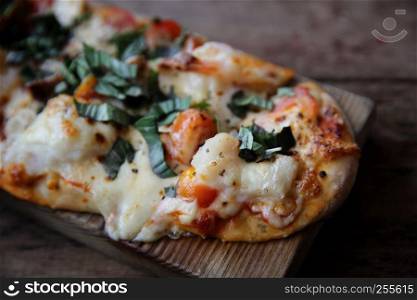 pizza with seafood and tomatoes on a wooden table , italian food