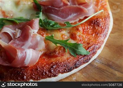 Pizza with smoked ham and rucola on wooden background .. Pizza with smoked ham and rucola on wooden background