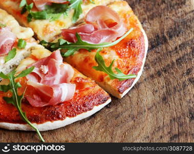 Pizza with smoked ham and rucola on wooden background .. Pizza with smoked ham and rucola on wooden background