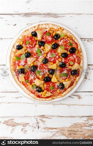 Pizza with tomatoes, mozzarella cheese, olives, corn and basil. Traditional italian cuisine. Top view