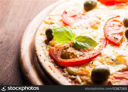 Pizza with tomatoes, olives and fresh basil, close up