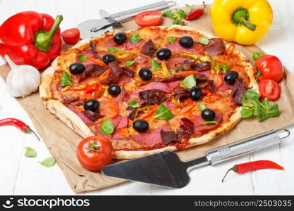 Pizza with vegetables and salami on wooden table with lifter and cutter knife