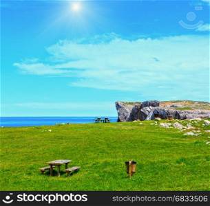 Place of rest (table with benches) on summer blossoming sunshiny coast near Camango, Asturias (Spain). Two shots stitch image.