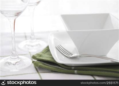 Place setting with white dishes and wine glasses
