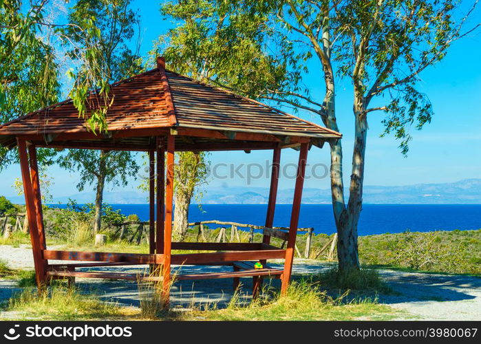 Place to relax for tourists in Greece. Benches under wooden shelter near sea, nature leisure spot.. Benches under shelter in Greece near sea