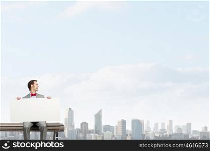 Place your text here. Young man sitting on bench with white banner