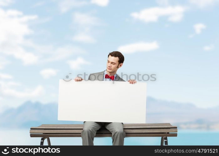 Place your text here. Young man sitting on bench with white banner