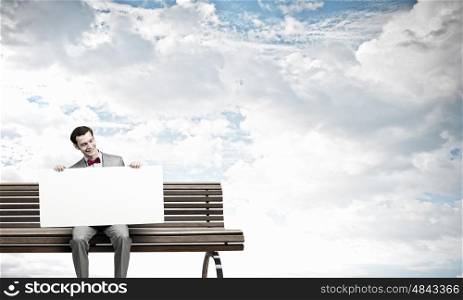 Place your text here. Young man sitting on bench with white banner