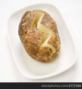 Plain baked potato sliced down the middle on a plate.
