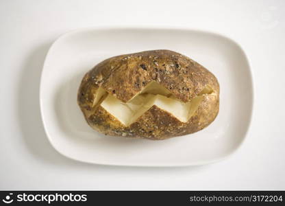 Plain baked potato sliced down the middle on a plate.