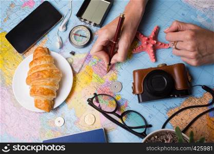 Plan of trip. background - what to take for a trip. Women's hands and map, retro camera, money, coins, croissant, coffee, pen, compass, sunglasses, smartphone