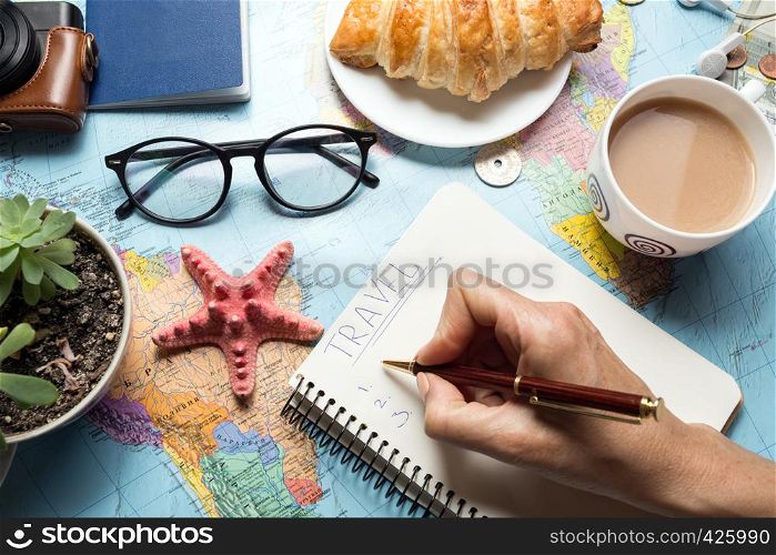 Plan of trip. background - what to take for a trip. Women's hands and notepad for writing ideas, map, retro camera, money, coins, croissant, coffee, pen, compass, sunglasses, smartphone