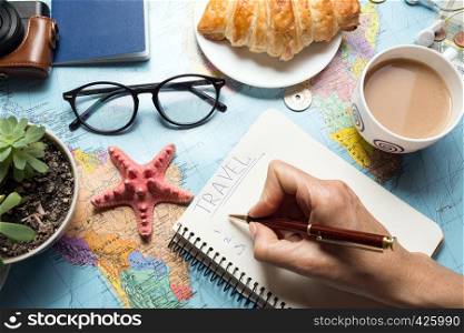 Plan of trip. background - what to take for a trip. Women's hands and notepad for writing ideas, map, retro camera, money, coins, croissant, coffee, pen, compass, sunglasses, smartphone