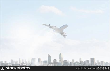 Plane flying in air. Passenger plane flying above modern city landscape