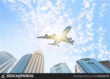 Plane in sky. Plane flying above skyscrapers. Business travel concept