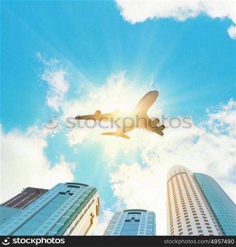 Plane in sky. Plane flying above skyscrapers. Business travel concept