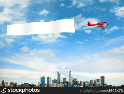 Plane in the sky above the city with blank flag