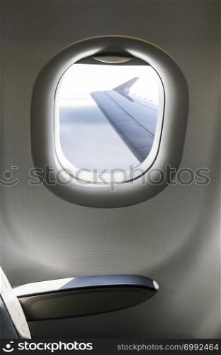 Plane interior sit and window. Airplane wing seen through the window. Air transport concept.