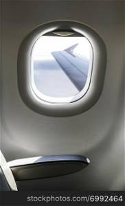 Plane interior sit and window. Airplane wing seen through the window. Air transport concept.