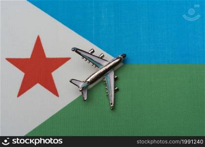 Plane over Djibouti flag, travel concept. Toy airplane on the flag as a background.. Toy airplane over the flag of Djibouti, the concept of journey.