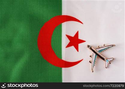 Plane over the flag of Algeria travel concept. Toy plane on a flag in the background.. Plane over the flag of Algeria travel concept.