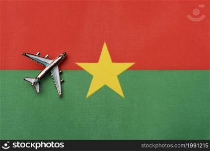 Plane over the flag of Burkina Faso, the concept of travel. Toy plane on the flag as a background.. Plane over the flag of Burkina Faso, the concept of travel.