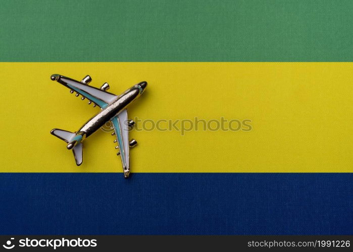 Plane over the flag of Gabon, the concept of travel. Toy plane on the flag as a background.. Plane over the flag of Gabon, the concept of travel.